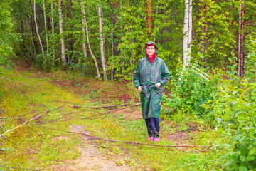 beautiful mature woman walking in the forest during the rain