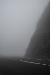 Foggy mountain road with a curve and dark silhouette of a person in background