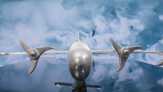 Macro lens view of silver model airplane with clouds in the background and video moving in.