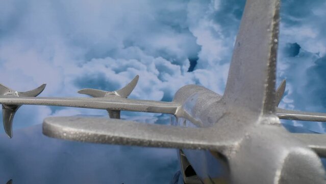 Macro lens view of silver model airplane from the back with clouds in the background and video moving in.