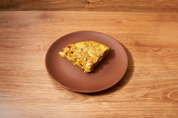 plate with a quarter of a potato omelette, sweet potato, zucchini, onion and pepper
