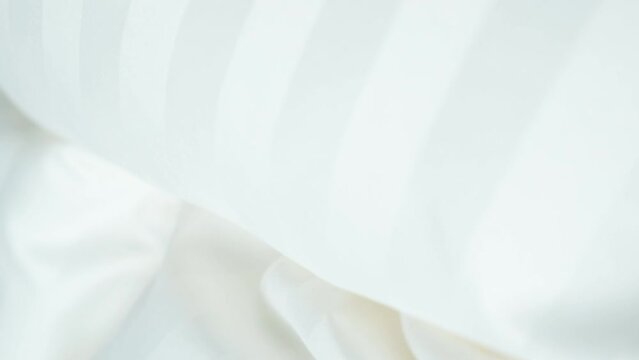 Beautiful moving background of light milky color, waves on fabric