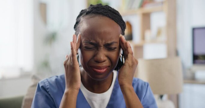 Stress, headache and black woman nurse on a sofa with burnout, pain or frustrated by mistake, loss or grief. Anxiety, regret or lady volunteer with burnout, vertigo or brain fog in consultation room