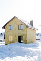 Country two-storey house in winter against the background of the sun, insulation of the house with mineral wool, energy-saving materials, cold winter.