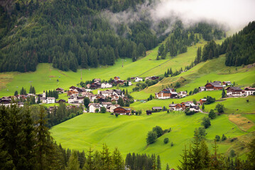 Fototapeta na wymiar Dolomite alps with a mountain village and green meadows