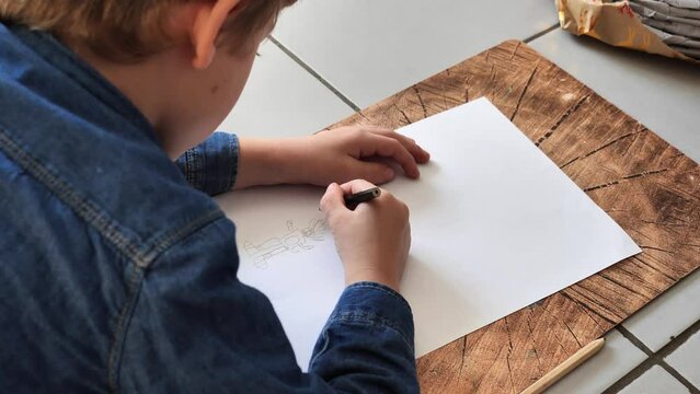  little boy draws while lying on the ground