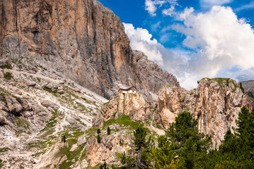 Fototapeta na wymiar Dolomite alps and a house or mountain refuge on rock above