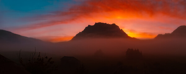 High resolution stitched alpine summer sunrise panorama with a foggy view of Mount Zugspitze at...