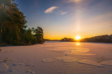 Fototapeta premium Sunrise of a frozen lake, with blue sky, thin cirrus layer, swedish late winter, near Stockholm. Forest and trees.