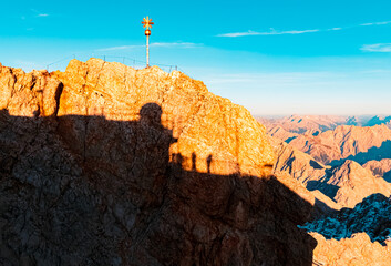 Alpine sunset or sundowner with a golden summit cross at Mount Zugspitze, Top of Germany,...