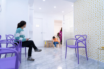 Waiting room of a dentist with a woman sitting and a child playing