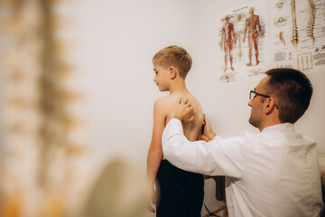 Doctor checking posture of little boy in clinic