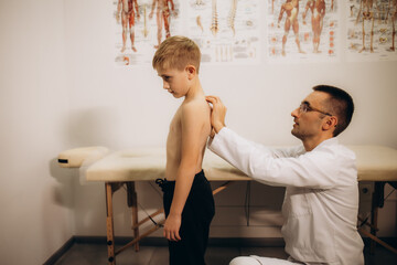 A pediatric neurologist doctor examines the back of a 5-year-old girl who has back pain. Treatment...