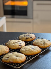 Close up of fresh baked chocolate chip cookies on baking rack on kitchen table, blurry background