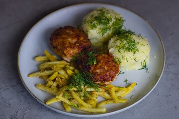 Traditional Polish meal: pork mince burgers served with mashed potatoes, yellow wax beans sautéed with breadcrumbs. Garnished with finely chopped dill.