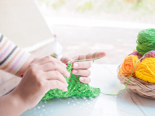 Close-up of woman hand knitting with green wool