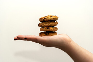 close-up detail of a woman's hand with outstretched palm and on it chocolate chip cookies on a white background