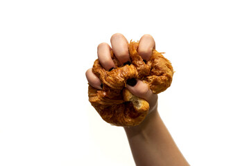 close-up detail of a young woman's hand crushing a croissant with her fingers tightly against a white background.