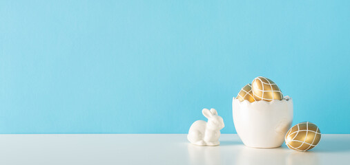 Easter table display, presenting a corner with a shell shaped bowl of gold eggs, and a hare figure...