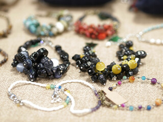 Handmade bracelet from multi-colored stones and beads on craft solid beige background