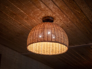 Wicker lamp on ceiling of wooden house