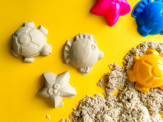 Beige kinetic sand for kids on yellow background, development and play at home with colorful...