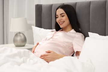 Happy pregnant woman in bed at home