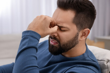 Fototapeta premium Unhappy man suffering from headache at home