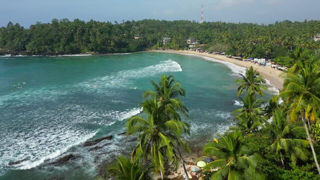 Tropical ocean lagoon with palms and turquoise water with waves good for surfing and full of surfers