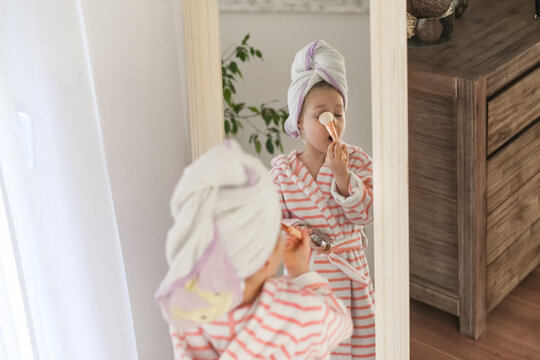 A little girl with a towel on her head doing makeup