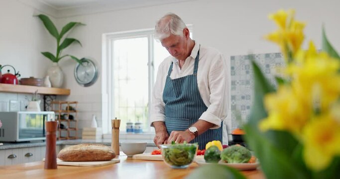 Cooking, kitchen and mature man with healthy food, nutrition and cutting vegetables in apron for lunch. Diet, wellness and home chef with ingredients for recipe, meal prep and dinner in apartment.