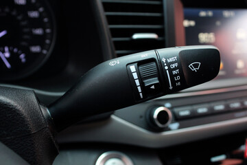 Close up on car rain windscreen wiper control stick. Modern car interior. Adjusting speed of screen wipers in car. Wiper switch toggle. - obrazy, fototapety, plakaty