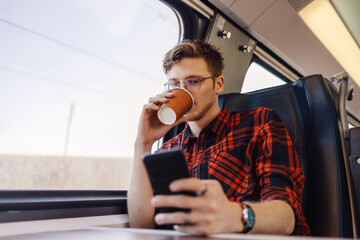 A young man is traveling by train, using his phone and typing on phone.
