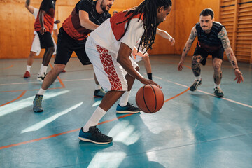 Interracial sportsman dribbling a ball on basketball training.