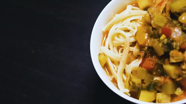 Stewed vegetables with meat and noodles in a bowl. Lagman. Black background.