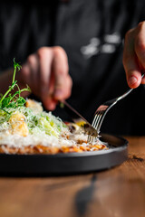 Hands of a man with a fork and knife eat Salad