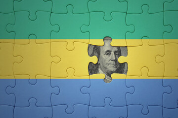 puzzle with the national flag of gabon and usa dollar banknote. finance concept