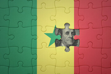 puzzle with the national flag of senegal and usa dollar banknote. finance concept