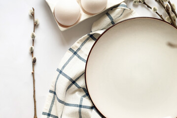 Easter table setting with empty white ceramic plate with cutlery  and spring willow branches on...