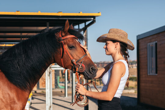 Woman taking care of his brown horse in an equestrian center