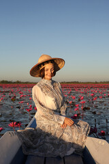 Beautiful woman, fashion girl in hat and lake with red lotuses in Udon Thani, Thailand. Nong Han Kumphawapi Lake or Red Lotus Lake (Talay Bua Daeng). Pink flowers, Thai nature, landmark. Thai scenery