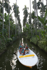 Fototapeta premium Beautiful woman with child, kid in boat in After the Rain Coffee & Gallery Cafe in Bangkok city, Thailand. Thai nature, landmark. Wild scenery, river