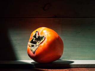 Image of ripe organic grown persimmon fruit in a wooden box in bright sunlight with copyspace. Natural fruit from garden concept image.