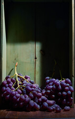 Bunch of ripe organic grown grapes in a wooden box in bright sunlight with copyspace. Natural fruit from garden concept image.