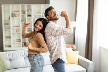 Young indian spouses dancing at home in living room, couple having fun, enjoying spending time...