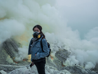The girl is wearing protecting mask in front of lake full of natural Sulfuric acid and hydrogen...