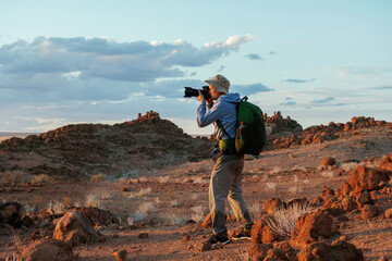 Using camera. Male tourist in casual clothes is in the deserts of Africa, Namibia