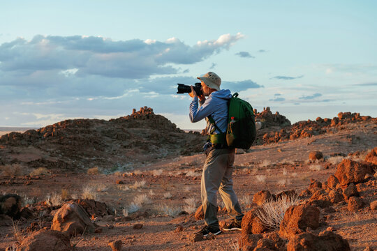 Using camera. Male tourist in casual clothes is in the deserts of Africa, Namibia