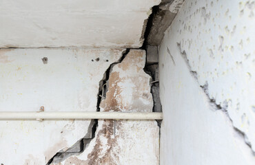 Cracked old brick plastered wall. House after the earthquake. Emergency building. Poor quality work during construction.