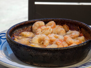 Traditional spanish shrimp with garlic, usually prepared with olive oil, side view wit copy space, cooked and served in a clay pot.
